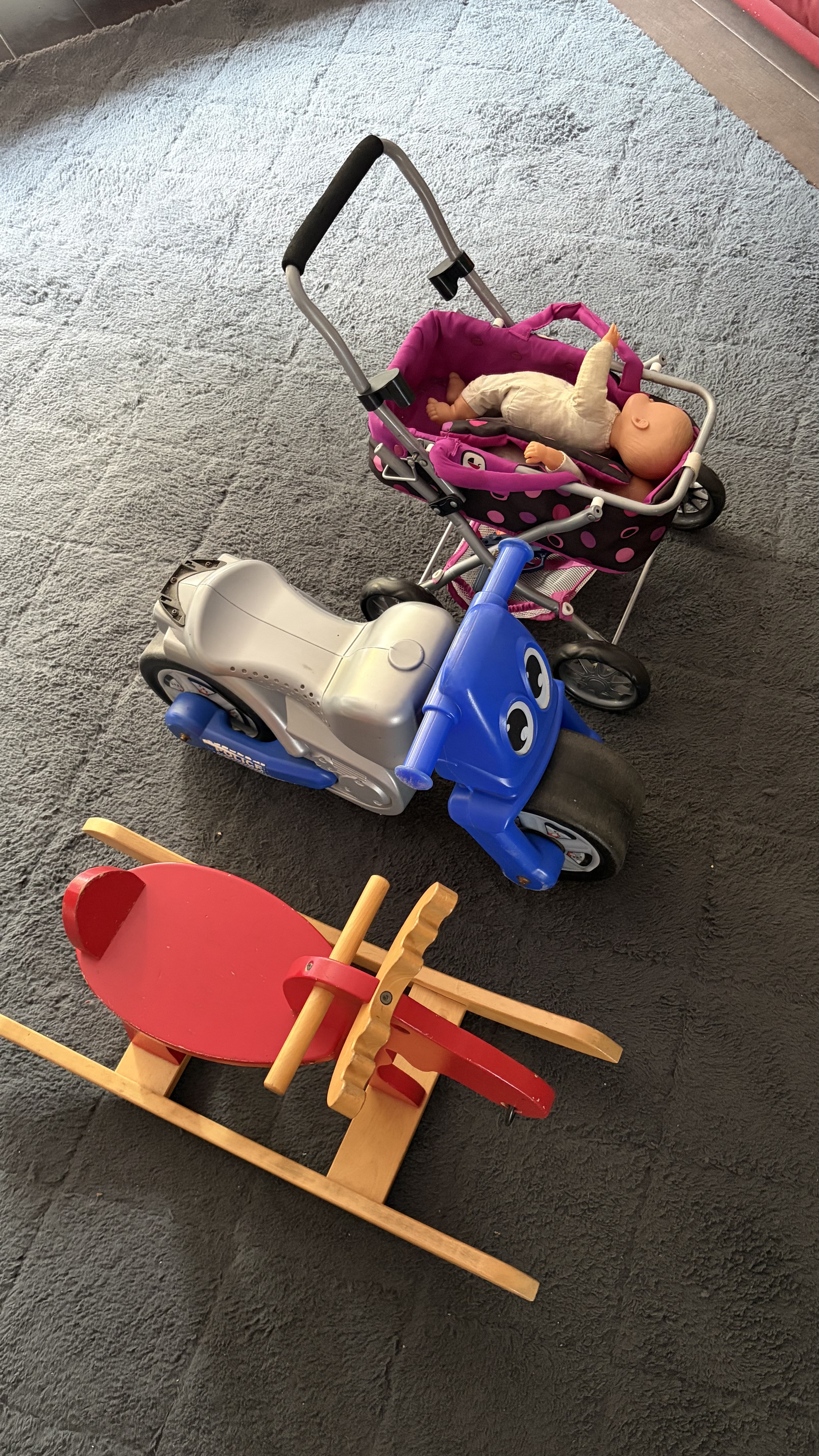 Spielzeug wie Puppenwagen und Rutschauto zum freien Spielen